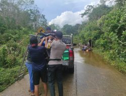 Bhabinkamtibmas Polsek Boyan Tanjung Bantu Pengendara Sepeda Motor Melewati Jalan yang Terendam Banjir