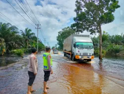 Personil Polres Pelalawan Berjibaku Bersama Masyarakat Timbun Jalan Rusak Akibat Banjir