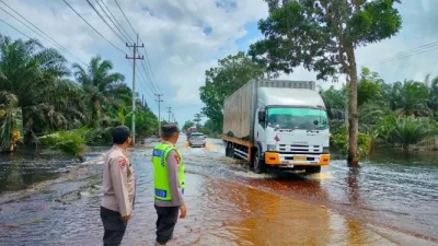 Personil Polres Pelalawan Berjibaku Bersama Masyarakat Timbun Jalan Rusak Akibat Banjir